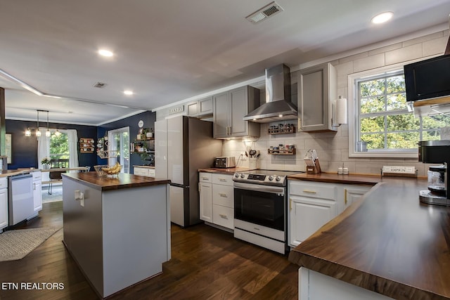 kitchen with stainless steel appliances, wooden counters, and wall chimney exhaust hood