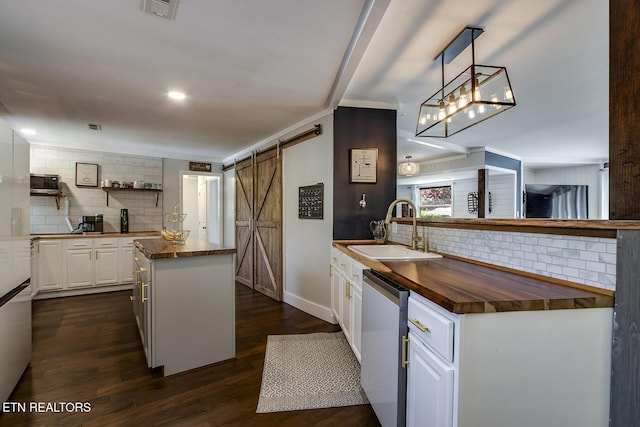 kitchen featuring a kitchen island, white cabinetry, sink, stainless steel dishwasher, and a barn door