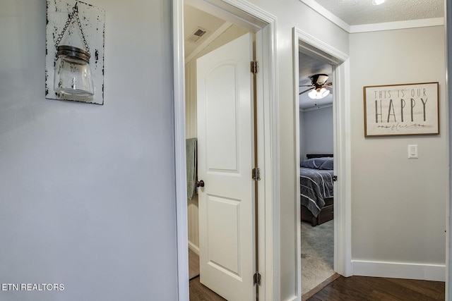 hallway with dark wood-type flooring and crown molding