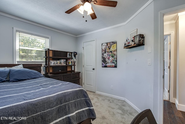 carpeted bedroom featuring crown molding, ceiling fan, and a textured ceiling