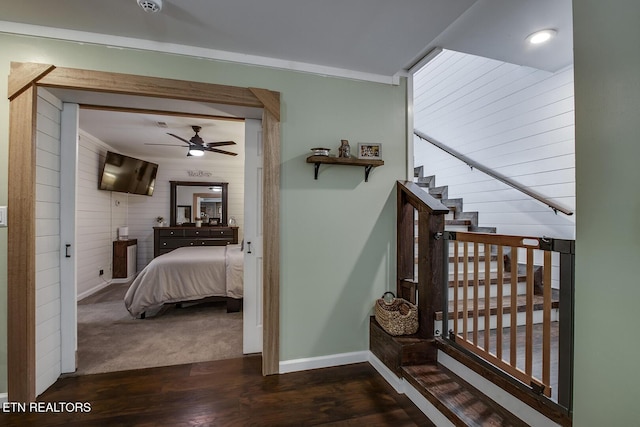 staircase with hardwood / wood-style floors, ceiling fan, and wood walls