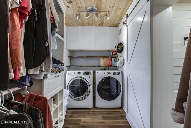 laundry area featuring dark hardwood / wood-style flooring, cabinets, a barn door, wooden ceiling, and washer and clothes dryer