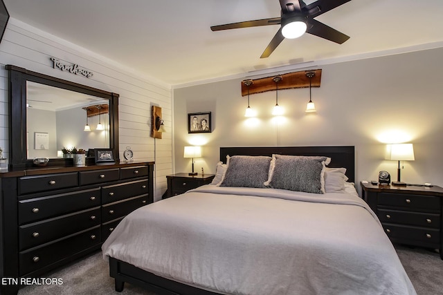 bedroom with ceiling fan, dark carpet, and wood walls