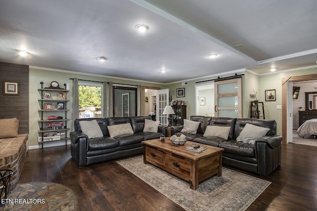 living room with crown molding, dark wood-type flooring, and a barn door