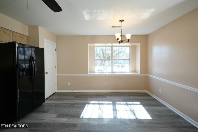 kitchen featuring visible vents, baseboards, black fridge, dark wood finished floors, and decorative light fixtures