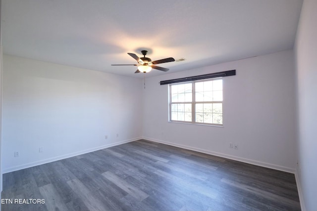 empty room with ceiling fan, dark wood finished floors, visible vents, and baseboards