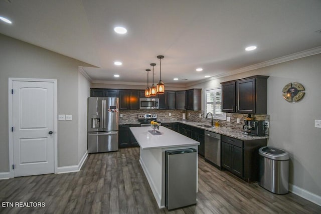 kitchen featuring pendant lighting, sink, backsplash, stainless steel appliances, and a kitchen island