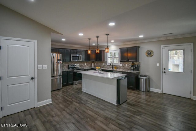 kitchen featuring sink, appliances with stainless steel finishes, backsplash, a kitchen island, and decorative light fixtures