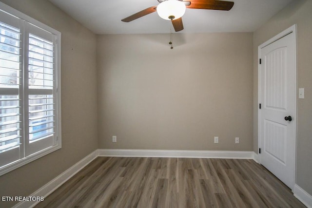 unfurnished room featuring dark wood-type flooring, a wealth of natural light, and ceiling fan