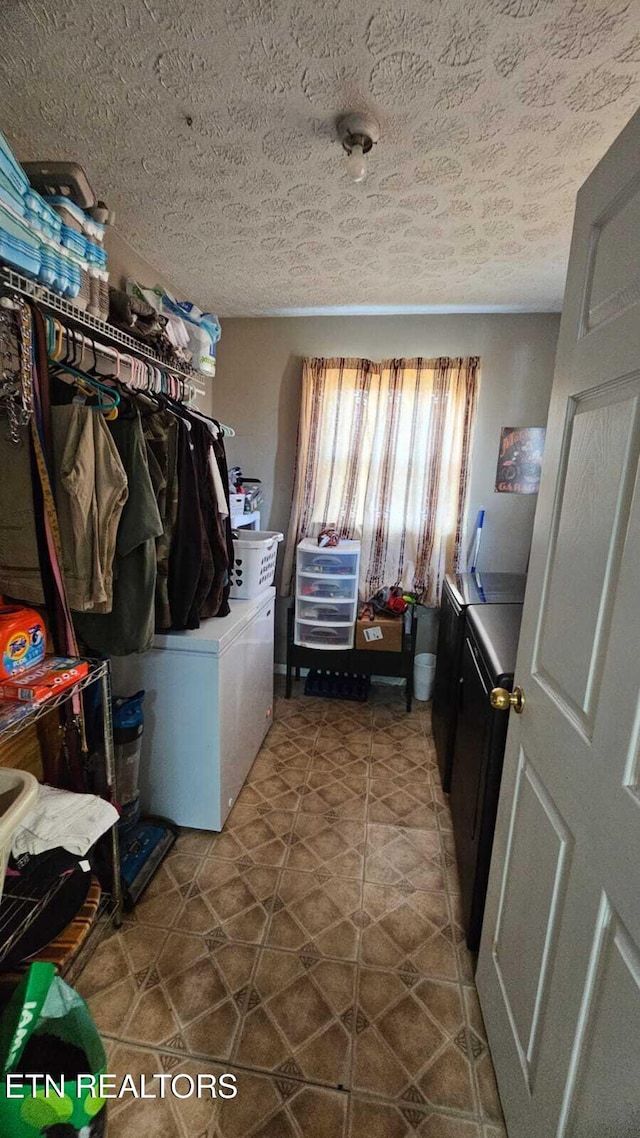 laundry room with tile patterned floors, washer and dryer, and a textured ceiling