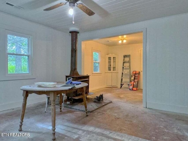 dining room featuring concrete floors, ceiling fan, and a wood stove