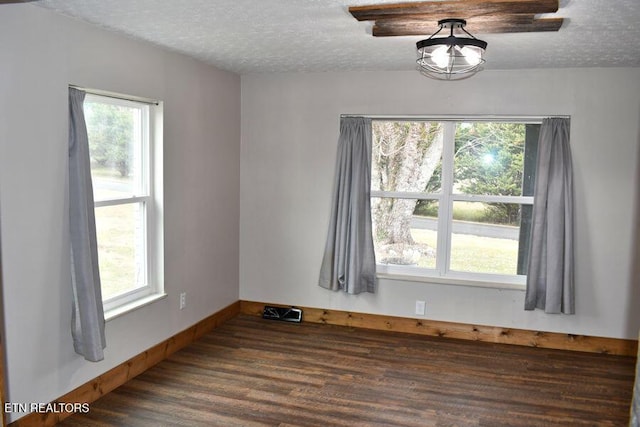 unfurnished room featuring plenty of natural light, dark hardwood / wood-style floors, and a textured ceiling