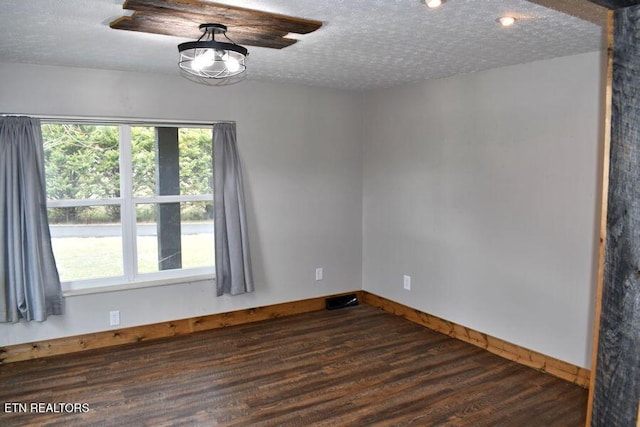 empty room featuring dark wood-type flooring and a textured ceiling