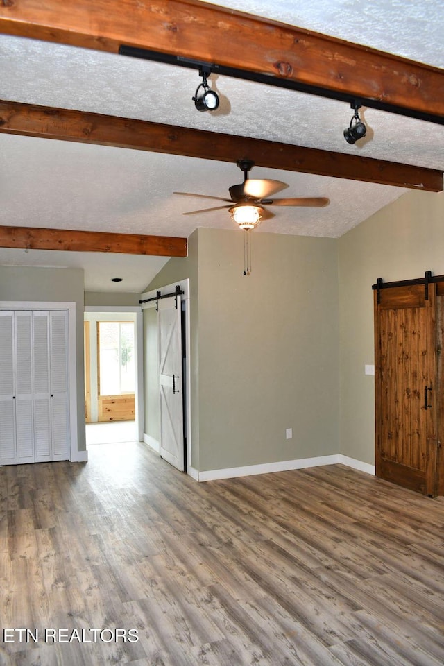 empty room featuring hardwood / wood-style flooring, a barn door, and a textured ceiling