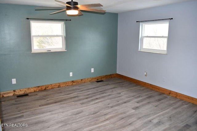 spare room with light hardwood / wood-style flooring, a wealth of natural light, and ceiling fan