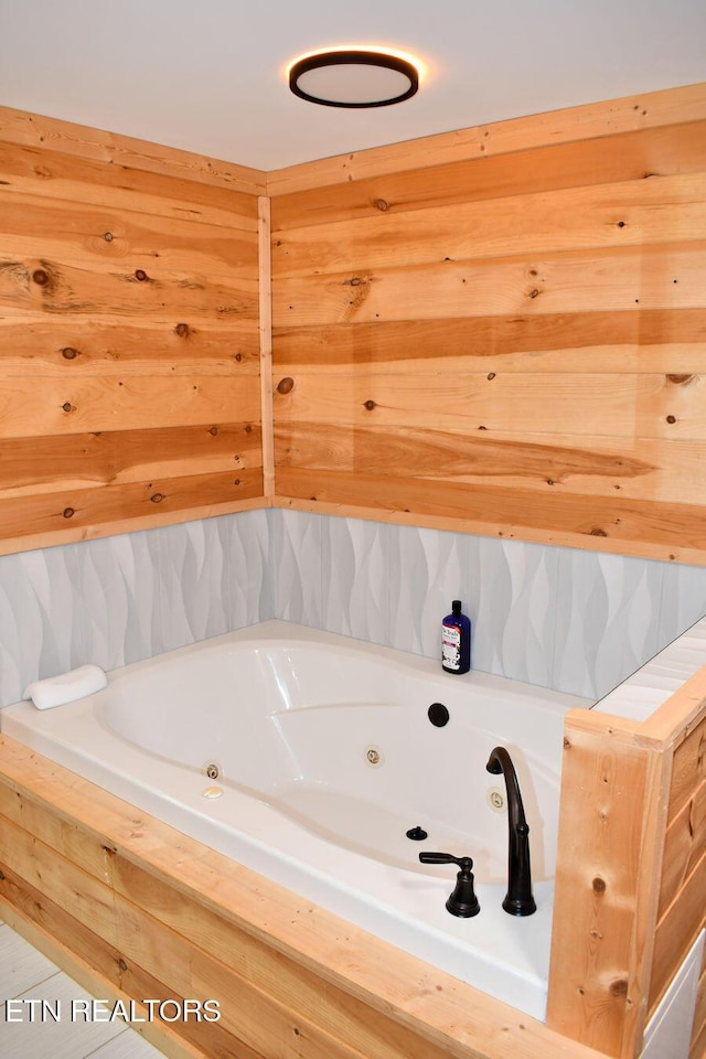 bathroom with tiled tub and wood walls