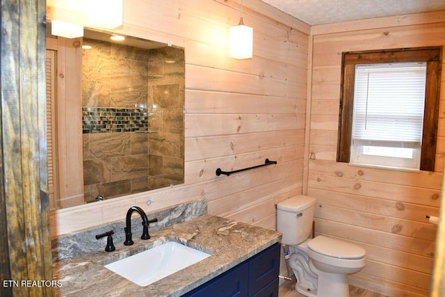 bathroom featuring vanity, toilet, and wood walls