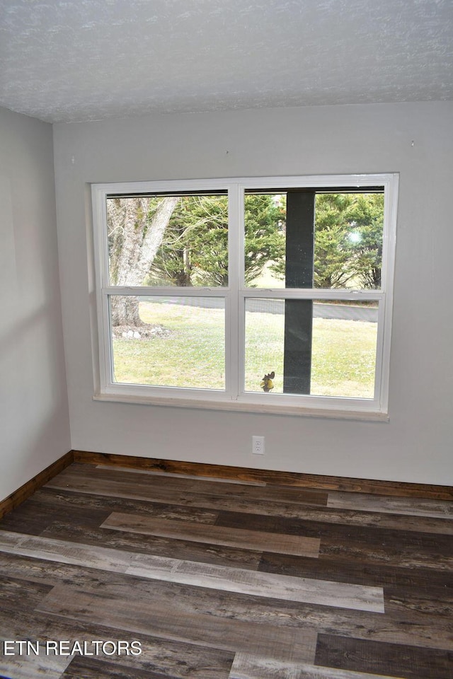 empty room with dark hardwood / wood-style flooring and a textured ceiling