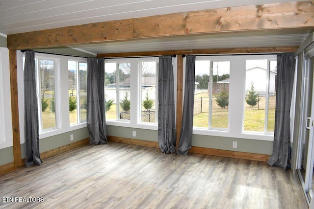 interior space with beam ceiling, plenty of natural light, and light hardwood / wood-style floors