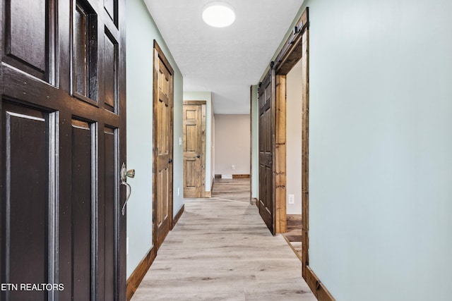 hall featuring light wood-type flooring and a barn door