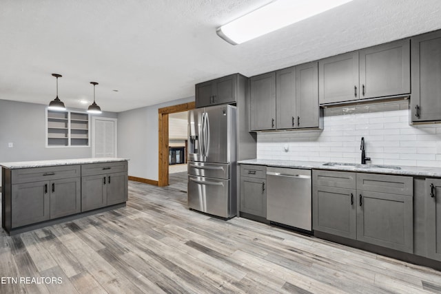 kitchen featuring decorative light fixtures, sink, stainless steel appliances, and gray cabinetry