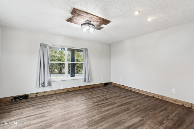 unfurnished room with hardwood / wood-style flooring and a textured ceiling