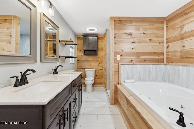 bathroom with vanity, tile patterned flooring, toilet, tiled bath, and wooden walls