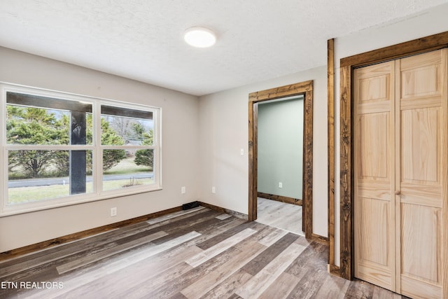 unfurnished bedroom featuring a textured ceiling, a closet, and wood-type flooring