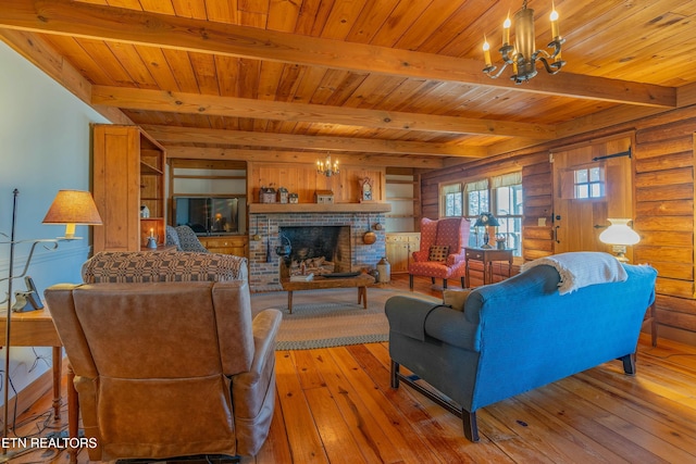 living room with an inviting chandelier, a fireplace, beam ceiling, and light wood-type flooring