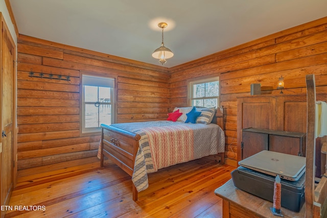 bedroom featuring rustic walls and light hardwood / wood-style flooring