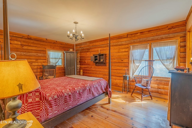 bedroom with an inviting chandelier, hardwood / wood-style floors, and rustic walls