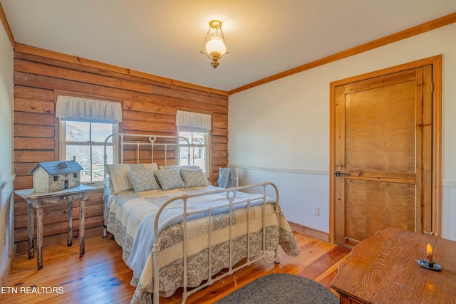 bedroom with ornamental molding, log walls, and light wood-type flooring