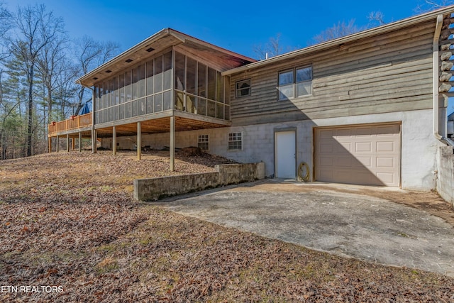 rear view of house with a garage and a sunroom