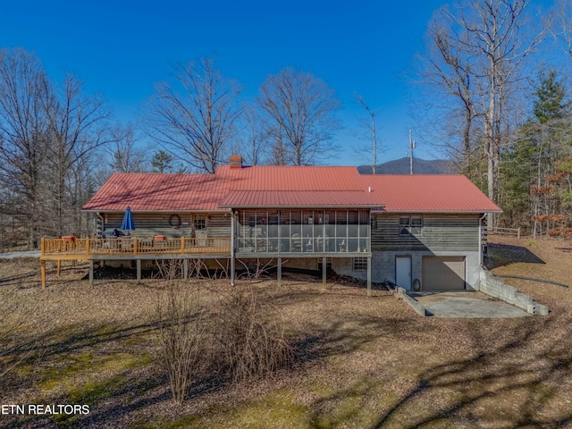 back of house featuring a garage, a sunroom, and a deck