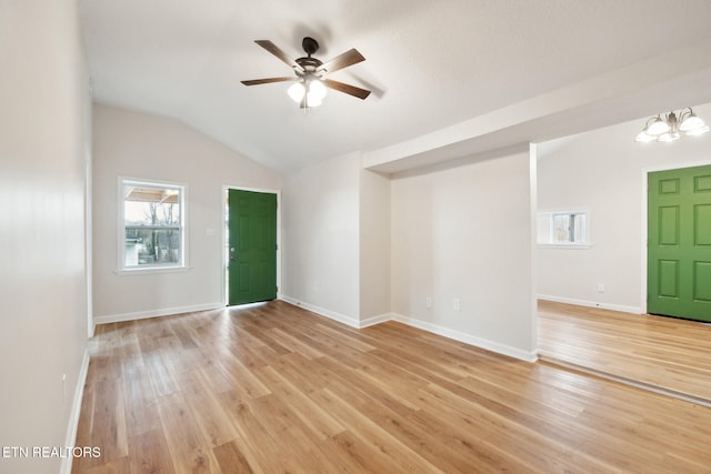 unfurnished room with lofted ceiling, ceiling fan with notable chandelier, and light hardwood / wood-style flooring