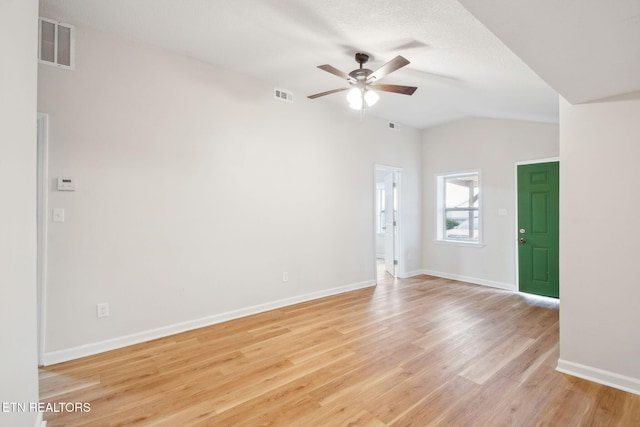 spare room with lofted ceiling, a textured ceiling, ceiling fan, and light wood-type flooring