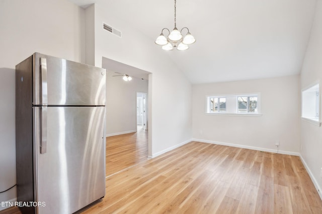 kitchen featuring an inviting chandelier, stainless steel refrigerator, lofted ceiling, hanging light fixtures, and light wood-type flooring