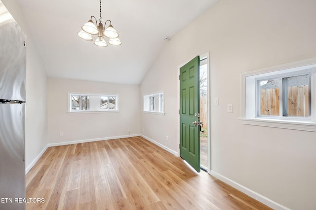 foyer with an inviting chandelier, lofted ceiling, and light wood-type flooring