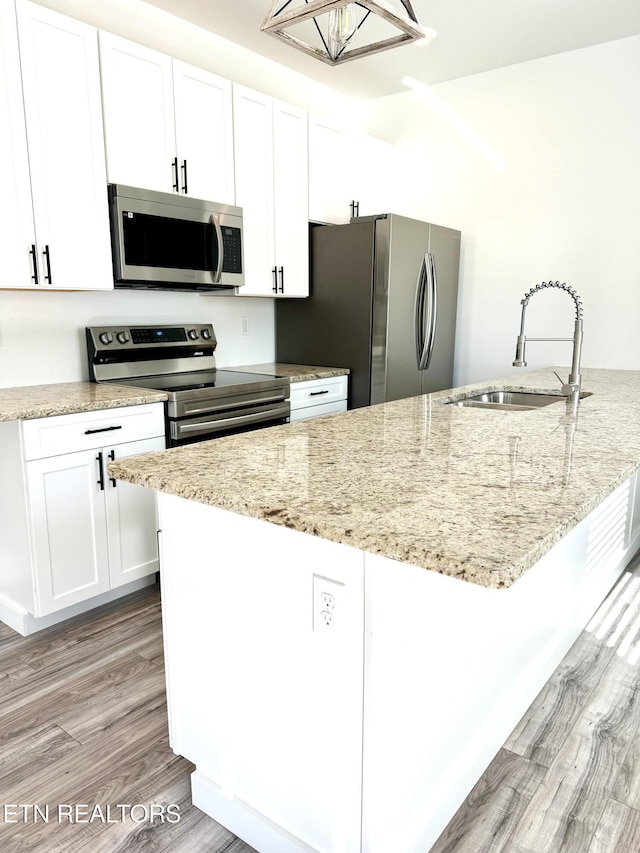 kitchen featuring sink, white cabinetry, light wood-type flooring, stainless steel appliances, and light stone countertops