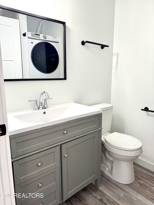 bathroom featuring toilet, wood-type flooring, washer / clothes dryer, and vanity