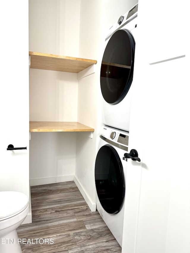 washroom featuring dark wood-type flooring and stacked washing maching and dryer