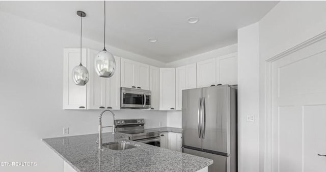 kitchen with sink, white cabinetry, appliances with stainless steel finishes, kitchen peninsula, and pendant lighting