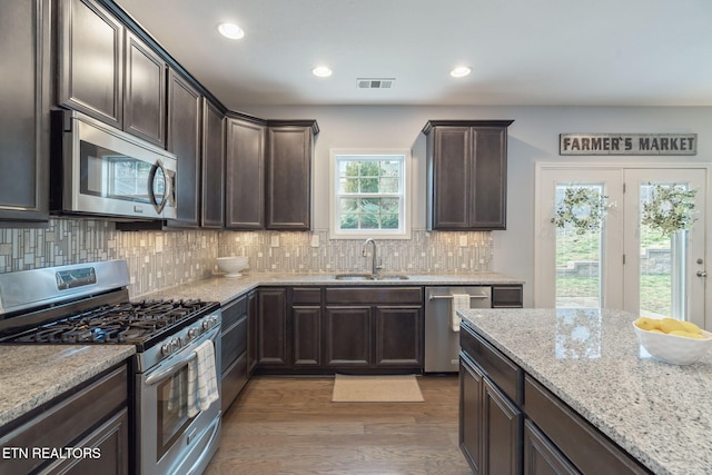 kitchen featuring sink, dark wood-type flooring, backsplash, dark brown cabinets, and stainless steel appliances