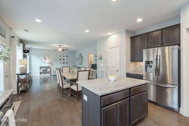 kitchen with tasteful backsplash, a center island, dark brown cabinets, dark hardwood / wood-style flooring, and stainless steel fridge