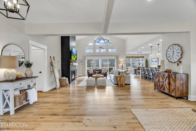 living room featuring beamed ceiling, a notable chandelier, light wood-type flooring, and a fireplace