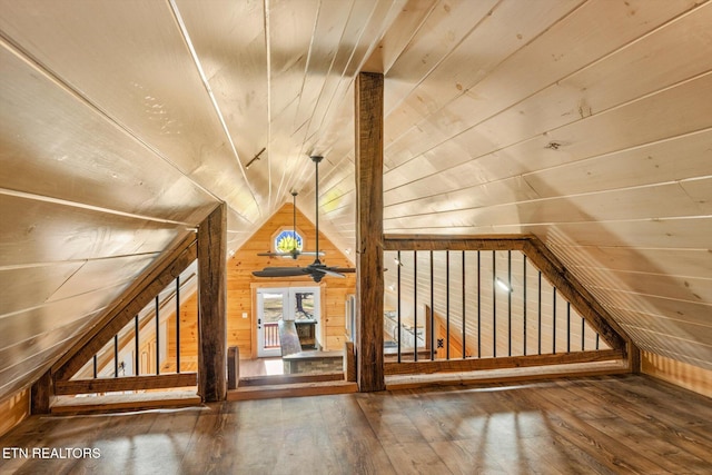 additional living space with lofted ceiling, wood-type flooring, and wood walls