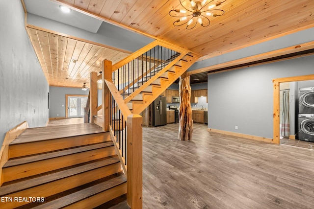 stairs with stacked washer and dryer, hardwood / wood-style flooring, sink, wooden ceiling, and a chandelier