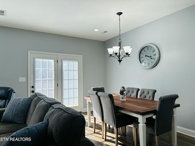 dining room featuring a notable chandelier, wood finished floors, visible vents, and baseboards