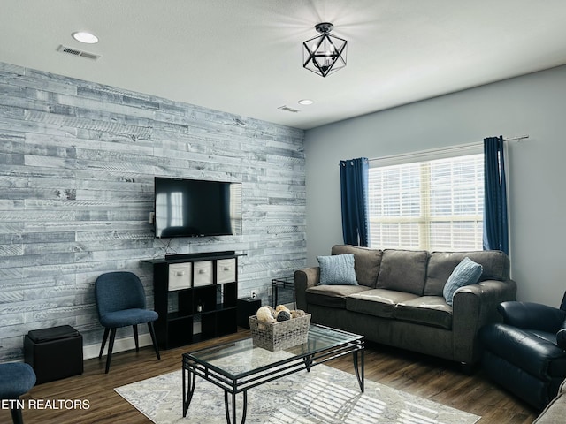 living area with an accent wall, visible vents, dark wood-type flooring, and recessed lighting