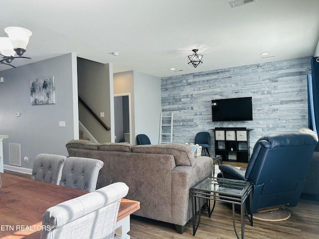 living room featuring an accent wall, wood finished floors, visible vents, baseboards, and wallpapered walls